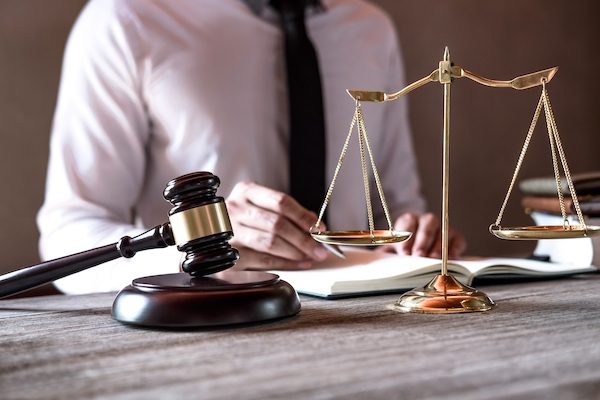 Legal law, advice and justice concept, Professional male lawyers working on courtroom sitting at the table and signing papers with gavel and Scales of justice.